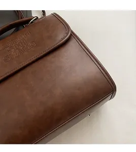 Close-up of brown textured leather backpack with embossed letters and precision stitching