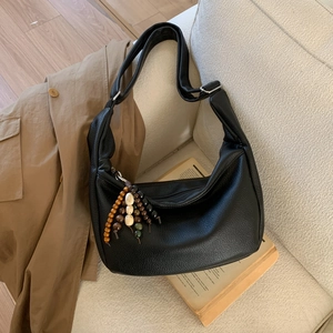 Detail of black crescent hobo bag featuring wide strap and colorful wooden bead charms