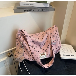 Détail du sac en velours rose avec motifs de cœurs noirs et charm de chien en peluche