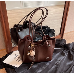 Detail of dark brown leather tote bag with metal logo and cute plush ice cream pendant