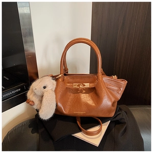 Détail du sac à main plissé marron avec fermoir doré et breloque lapin en peluche