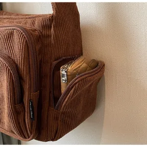 Detail of brown corduroy tote bag side zipper pocket showing storage for a wallet