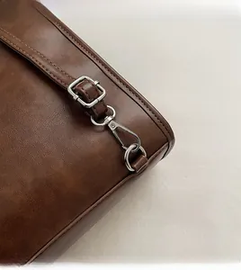Detail of adjustable metal buckle and detachable hook on vintage brown leather bag