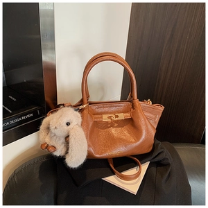 Détail du sac plissé caramel avec boucle dorée et breloque lapin en peluche mignonne