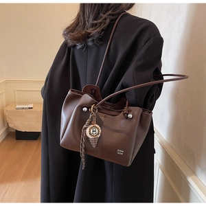 Detail view of large brown tote bag with leather texture and ice cream charm