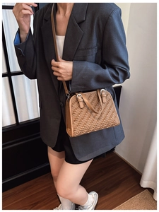 Bolso bandolera marrón con textura de espiga lucido por modelo en un traje elegante