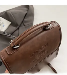 Detail of vintage brown leather handbag featuring comfortable handle and embossed lettering