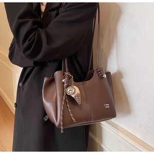 Detailed view of a dark brown tote bag with ice cream charm on a female model