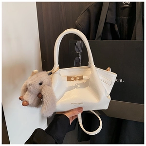 Détail du sac en cuir blanc avec boucles dorées et charm lapin en peluche doux