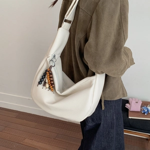 Detail of cream crescent bag featuring lychee texture and colorful wooden bead charms