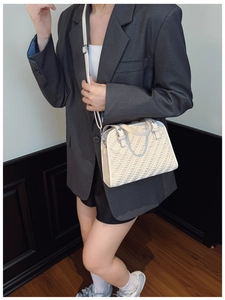 Detalle de la textura trenzada crema en bolso bandolera con blazer gris de gran tamaño