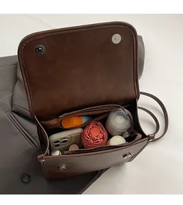 Macro shot of large capacity interior with phone and umbrella in brown leather crossbody bag