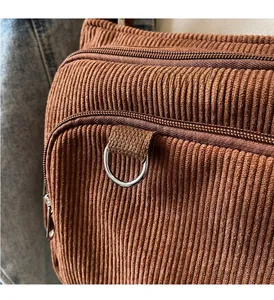 Close-up of caramel corduroy tote bag featuring dual zippers and silver D-ring hardware