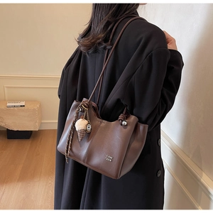 Detail view of brown leather tote bag featuring brand logo and ice cream charm decoration
