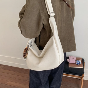 Detail of white lychee texture leather shoulder bag with natural wooden bead charm accessory