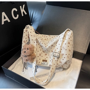 Détail du sac cabas en velours côtelé crème avec motifs de cœurs et breloque ours en boîte
