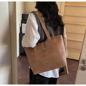 Side view of a vintage brown leather tote bag with long straps worn by a model