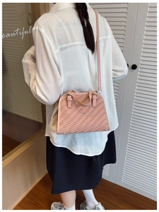 Detalle de bolso rosa con textura trenzada que incluye asas superiores y bandolera
