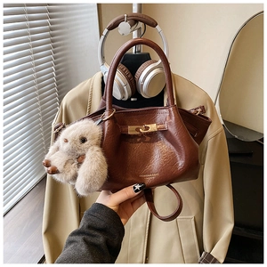 Détail du sac à main marron plissé en cuir avec fermoir doré et breloque lapin doux