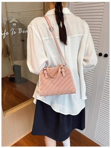 Detalle de bolso bandolera rosa con textura trenzada usado por modelo con top blanco