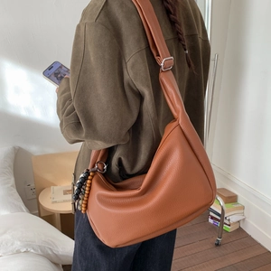Detailed close-up of brown pebbled hobo bag with wide strap and wood bead accessory