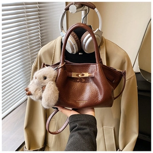 Détail d'un sac à main plissé marron avec fermoir doré et pendentif lapin doux