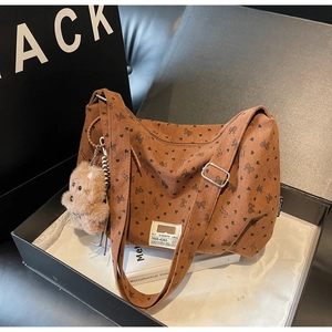 Détail d'un sac cabas en velours marron avec motifs papillons et breloque ourson