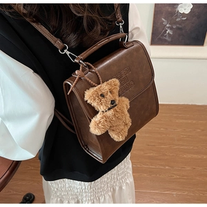 Close-up of vintage brown matte leather handbag with cute plush bear charm detail