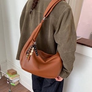 Detail of a brown lychee pattern leather hobo bag with colorful vintage beaded charm