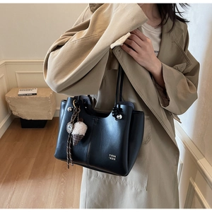Detail of black matte leather tote bag with silver logo and ice cream charm accessory