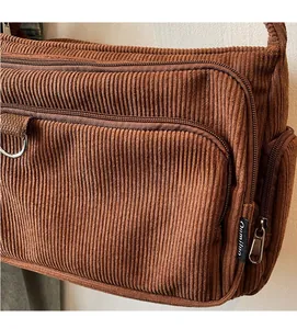 Detail of brown corduroy tote bag showing multiple zipper compartments and texture