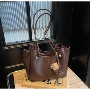 Detail of dark brown leather tote bag with silver beads and plush ice cream pendant charm