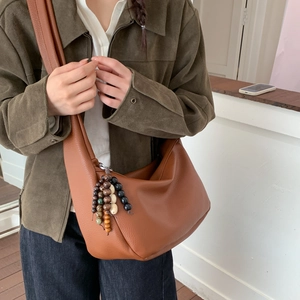 Detail of dark brown leather tote with pebble texture and beaded charm on model