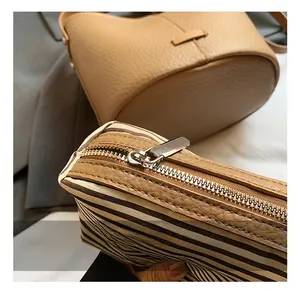 Detail of silver metal zipper and leather trim on khaki lychee grain bucket bag