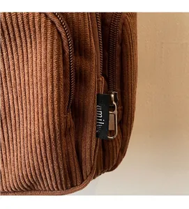 Detail of dark brown corduroy tote bag showing ribbed texture and zipper finish