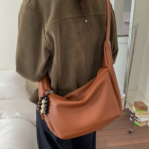 Detail of caramel hobo bag with textured leather and retro wooden bead charm