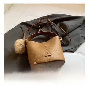 Detail view of brown lychee-pattern bucket bag with fluffy pompom charm for work