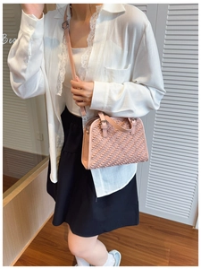 Detalle de textura de bolso bandolera trenzado rosa con correa ajustable en modelo