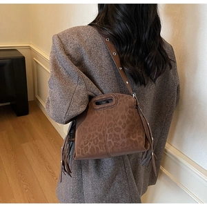 Détail du sac léopard en faux daim avec pompons latéraux et poignée découpée élégante