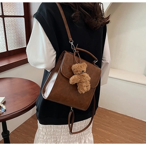 Dettaglio dello zaino vintage in pelle PU marrone con ciondolo a forma di orsetto di peluche