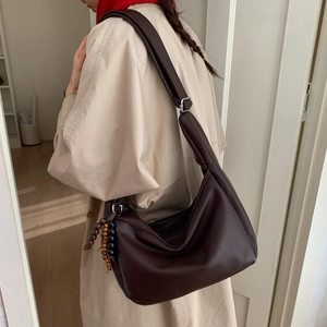 Detail of dark brown leather hobo bag with textured finish and wooden bead pendant
