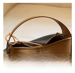 Close-up of brown pebbled leather bucket bag featuring a soft fur ball charm detail