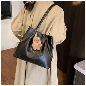 Detail einer großen schwarzen Leder-Tote mit einem niedlichen braunen Plüschhund-Anhänger