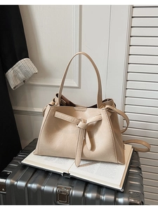 Detail of beige tote bag with signature knotted strap on a metal suitcase