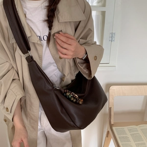 Detail of deep brown pebble leather hobo bag with colorful beaded zipper pull