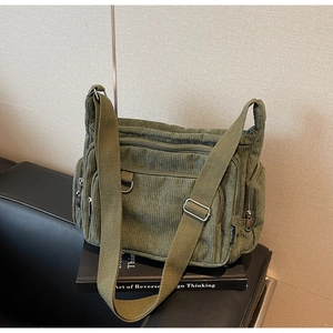 Detailed macro view of army green corduroy texture and multiple functional zippers on tote bag