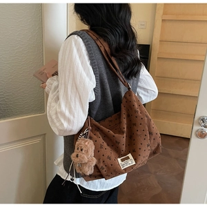 Détail du sac cabas en velours marron avec motifs de cœurs noirs et charm chien peluche