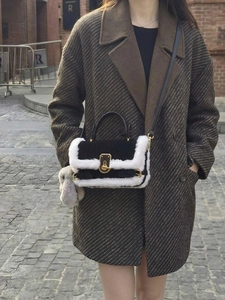Dettaglio borsa in pelle nera con bordo in ecopelliccia bianca e ciondolo a coniglio