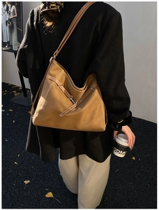 Detailed view of brown leather tote bag with decorative cross straps and metal hook hardware