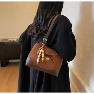 Detailed view of suede patchwork bag with leather bow and heart pendant detail